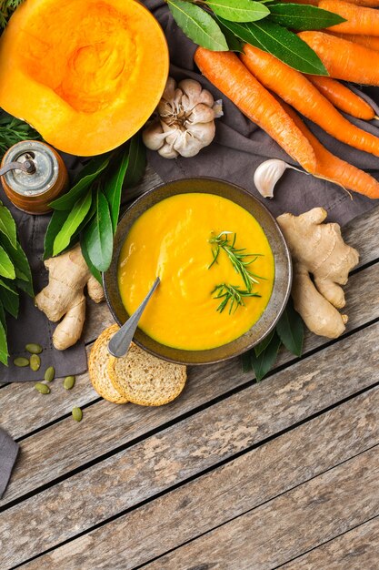 Comida sana, concepto de alimentación limpia. Vegetales de otoño picantes de temporada cremosa sopa de calabaza y zanahoria con ingredientes sobre una mesa de madera rústica. Fondo de espacio de copia plana laicos vista superior