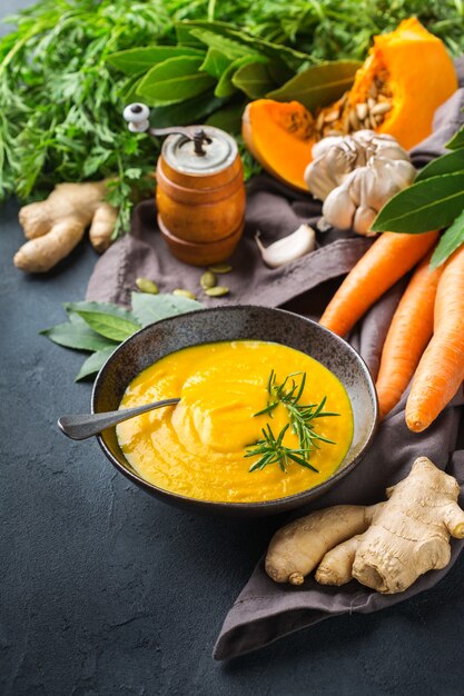 Comida sana, concepto de alimentación limpia. Vegetales de otoño picantes de temporada cremosa sopa de calabaza y zanahoria con ingredientes sobre una mesa.