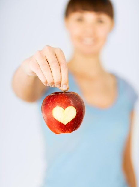 Foto comida sana y estilo de vida - mano de mujer sosteniendo manzana roja con forma de corazón