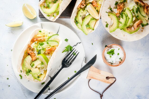 Comida sana merienda. Taco de tortillas con pollo a la parrilla, aguacate, salsa fresca, lechuga, lima. Con yogurt y salsa de perejil. Sobre la mesa de mármol de piedra gris claro, placa de mármol. Copia espacio vista superior