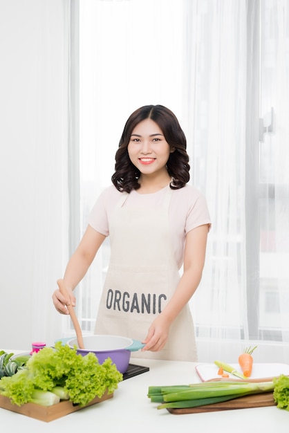 Comida sana. Mujer asiática cocinando en la cocina con cuchara de madera