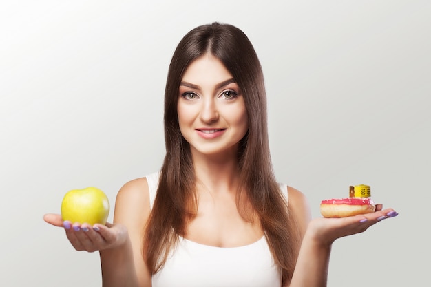 Comida sana. La mujer está perdiendo peso. Una joven duda entre elegir comida o hacer deporte.