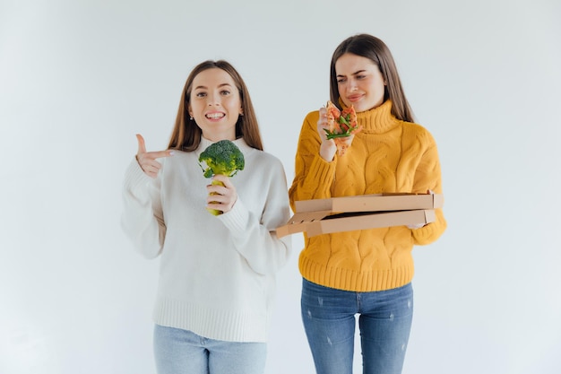 Comida sana. Una mujer sostiene una pizza y la otra un brócoli.