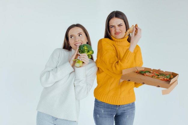 Comida sana. Una mujer sostiene una pizza y la otra un brócoli.