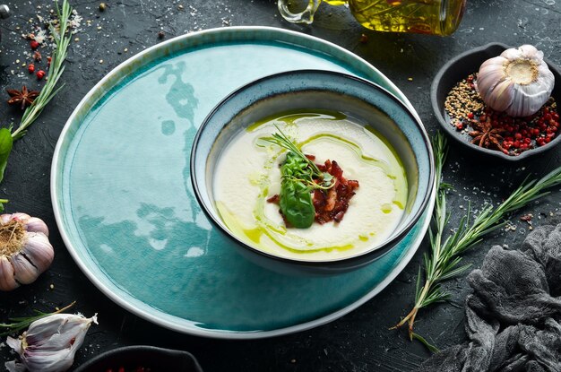 Comida sana Sopa cremosa con tocino y albahaca en un plato sobre un fondo de piedra negra Vista superior Estilo rústico