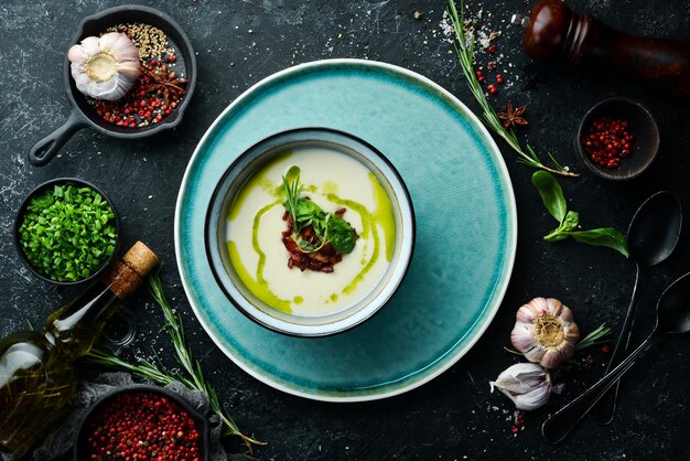 Comida sana Sopa cremosa con tocino y albahaca en un plato sobre un fondo de piedra negra Vista superior Estilo rústico