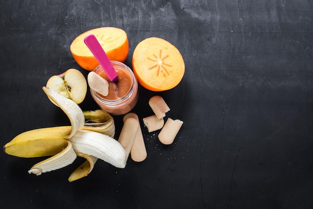 Comida sana. Yogur de frutas o puré en vidrio con diferentes frutas sobre fondo negro. Vista superior. copia espacio