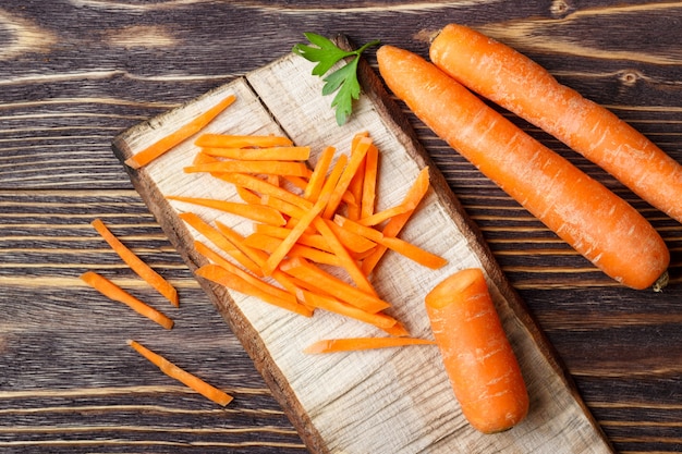 Comida sana - zanahoria entera y en rodajas sobre fondo de madera.