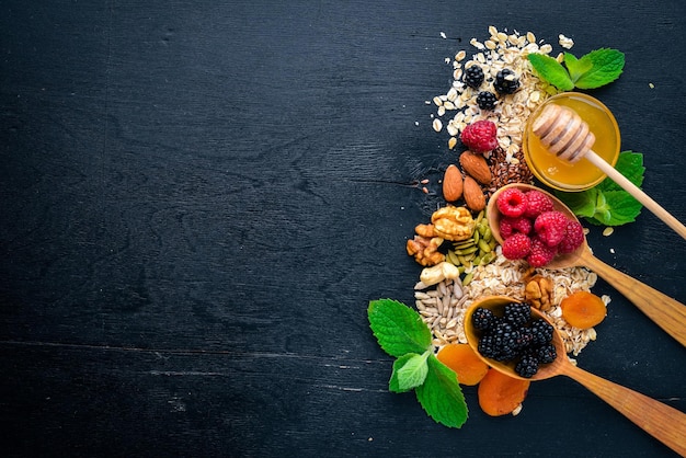 Foto comida saudável bagas silvestres frescas cobre nozes aveia frutas secas e sementes em um fundo de madeira vista superior espaço livre para texto