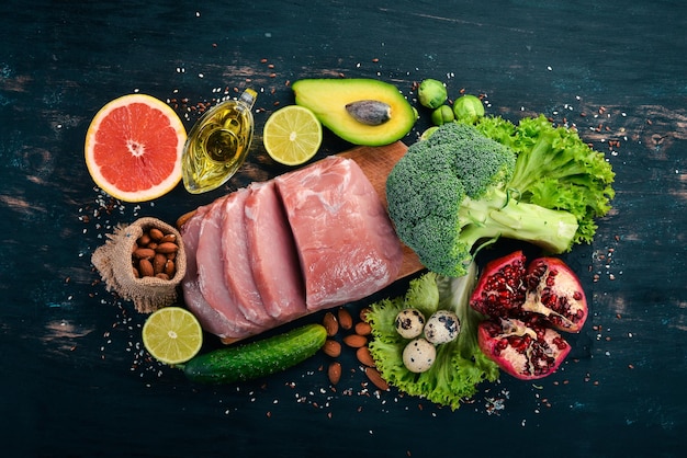 Comida saudável Carne crua abacate brócolis legumes frescos nozes e frutas Em um fundo de madeira Vista superior Copiar espaço