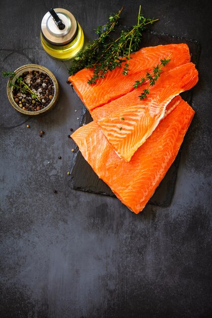 Comida saudável de peixe fresco filé de salmão cru tomilho e especiarias em uma mesa de pedra escura copiar espaço