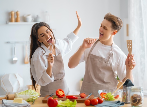 Foto comida saudável em casa. feliz casal apaixonado está preparando a refeição adequada na cozinha.