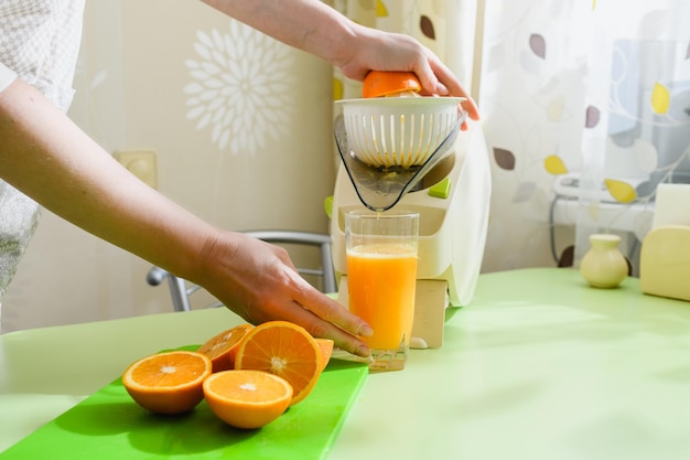 Comida saudável em casa mulher está preparando suco de laranja fresco na cozinha