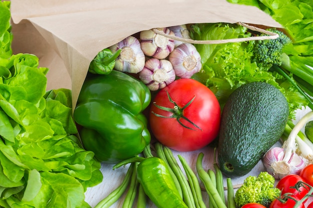 Comida saudável em saco de papel de diferentes vegetais em branco. Vista do topo