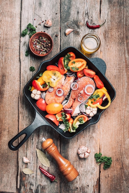 Comida saudável Jantar ingredientes para cozinhar Peixe salmão cru cru com legumes ervas especiarias em panela de grelhar de ferro sobre fundo de madeira Espaço de cópia de vista superior