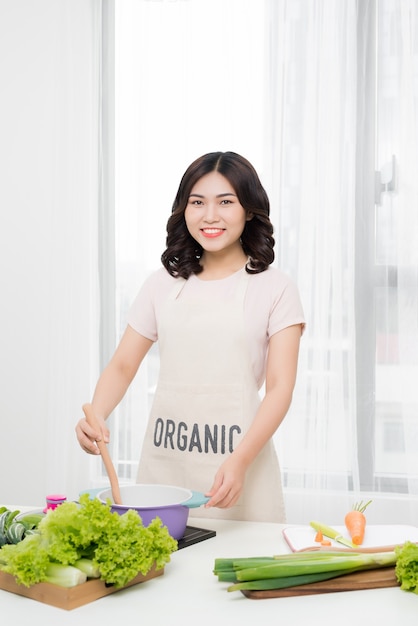 Comida saudável. Mulher asiática cozinhando na cozinha com colher de pau