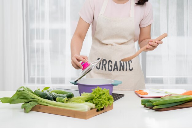 Comida saudável. Mulher asiática cozinhando na cozinha com colher de pau