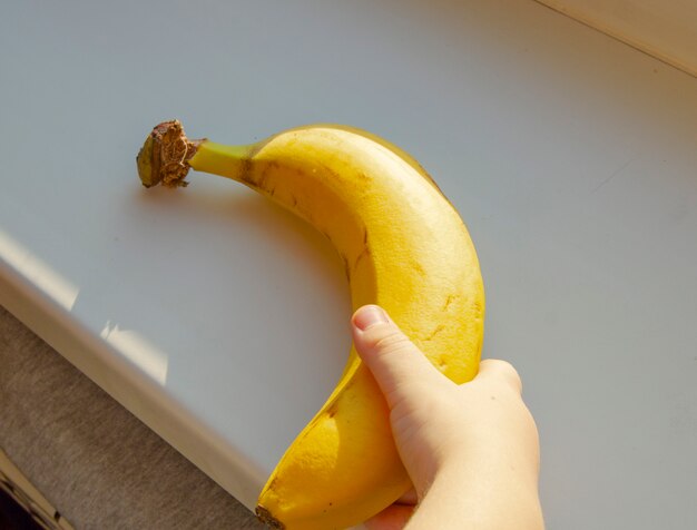 Comida saudável para as crianças. mão de crianças segurando uma banana