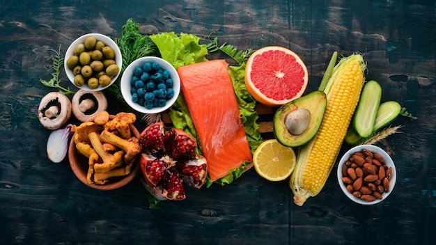 Comida saudável peixe nozes legumes frescos e frutas em uma velha mesa de madeira vista superior espaço livre para texto