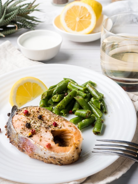 Comida saudável. peixe vermelho assado, salmão rosa, salmão e feijão verde com uma fatia de limão em um prato