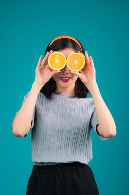 Comida saudável Sorrindo linda garota asiática pinup segurando laranja sobre fundo azul