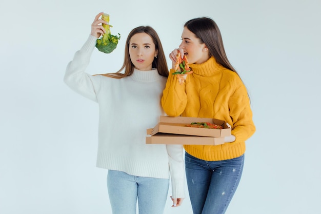 Comida saudável. Uma mulher está segurando uma pizza e a outra um brócolis