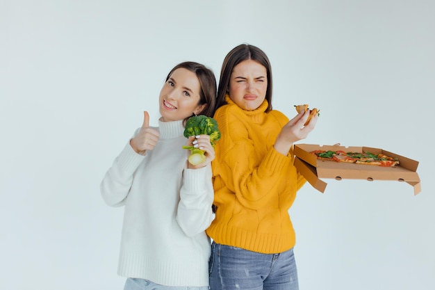 Comida saudável. Uma mulher está segurando uma pizza e a outra um brócolis