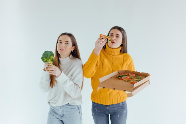 Comida saudável. Uma mulher está segurando uma pizza e a outra um brócolis