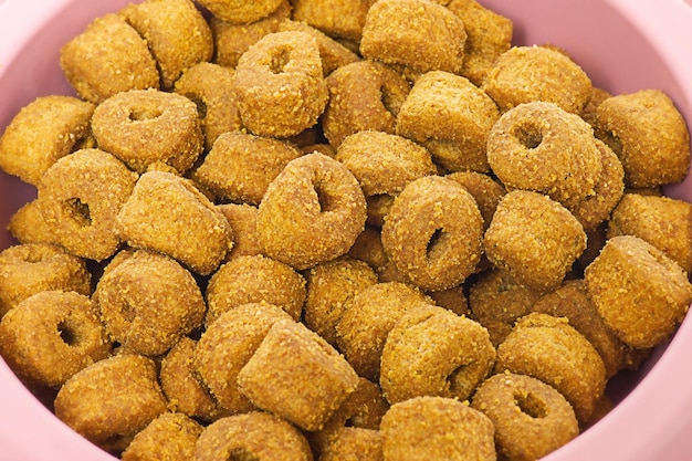 Comida seca para gatos o perros macro foto Alimentación animal en un tazón rosa