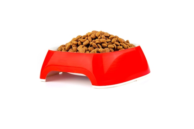 Comida seca para gatos y perros en un recipiente rojo sobre un fondo blanco.