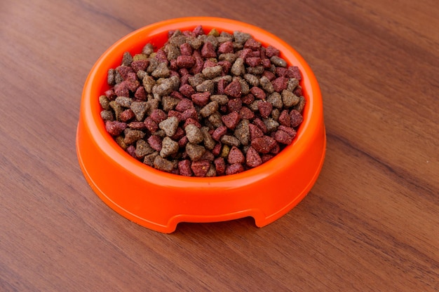 Comida seca para gatos en un tazón sobre fondo de madera. Alimentos para mascotas en la superficie de la madera. Vista superior