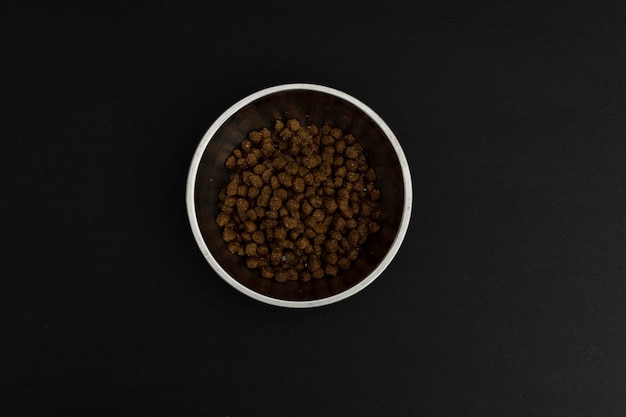 Comida seca para perros en una placa de aluminio sobre una comida para perros de fondo negro