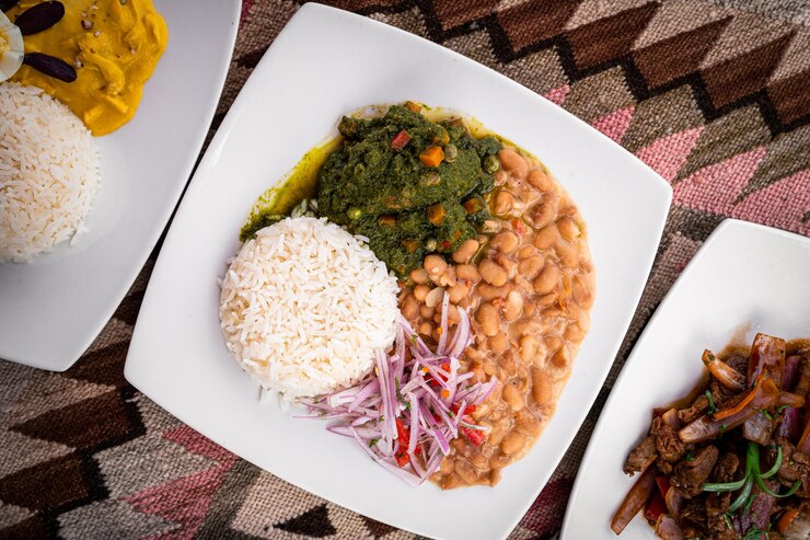 Comida servida en platos blancos y mesa artesanal.