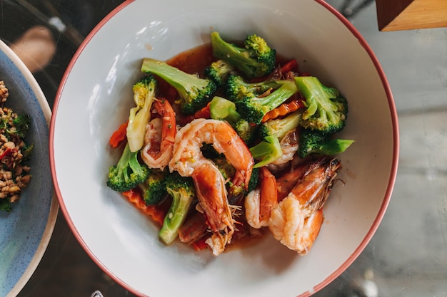 Comida tailandesa brócoli salteado con camarones en plato blanco