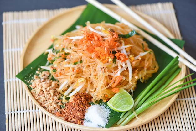 Comida tailandesa macarrão frito estilo tailandês com camarão broto de feijão e enfeite amendoim pimenta açúcar em pó limão limão, macarrão salteado Pad Thai no prato servido na mesa de jantar comida - vista superior