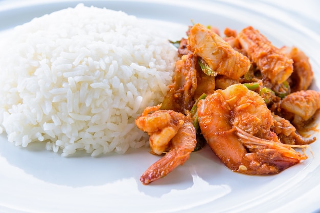 Comida tailandesa picante, vista lateral do close up da comida da Ásia Camarão Curry vermelho frutos do mar fritos, curry de camarão frito e leite de coco com arroz branco em um fundo de prato redondo e branco limpo para cozinhar refeições deliciosas