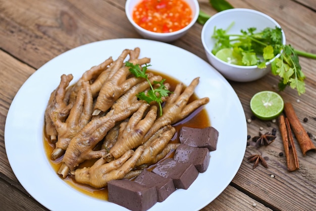 Comida tailandesa sopa de pés de galinha guisado cozinhando guisado de pés de frango em branco com ingredientes de ervas e especiarias com vegetais de limão pimenta em fundo de madeira Guisado de menu de comida chinesa asiática