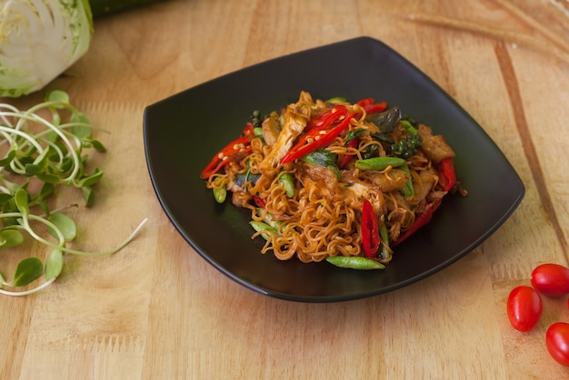 Comida tailandesa vegetariana, tallarines de arroz salteados picantes, en fondo de madera