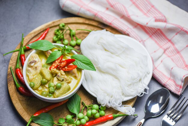 Comida tailandesa verde curry frango na tigela de sopa e macarrão de arroz tailandês aletria com ingrediente vegetal de ervas - comida asiática em cima da mesa