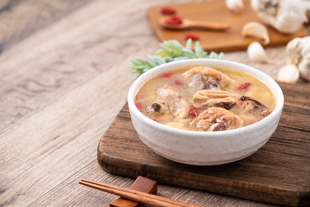 Comida taiwanesa - canja de galinha caseira deliciosa com alho em uma tigela no fundo da mesa de madeira escura.