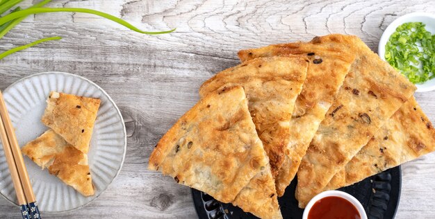 Comida taiwanesa: deliciosos panqueques de pastel de cebolleta escamosa sobre fondo de mesa de madera brillante, bocadillo tradicional en Taiwán, vista superior.