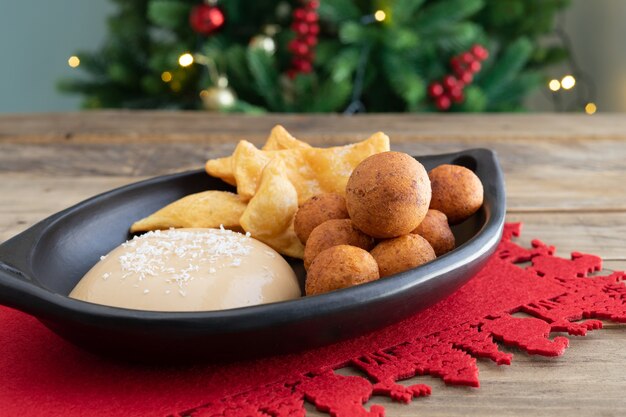 Comida típica colombiana. Buñuelo, natillas y hojuelas con velas y árbol de Navidad de fondo. Fiesta colombiana. Copie el espacio.