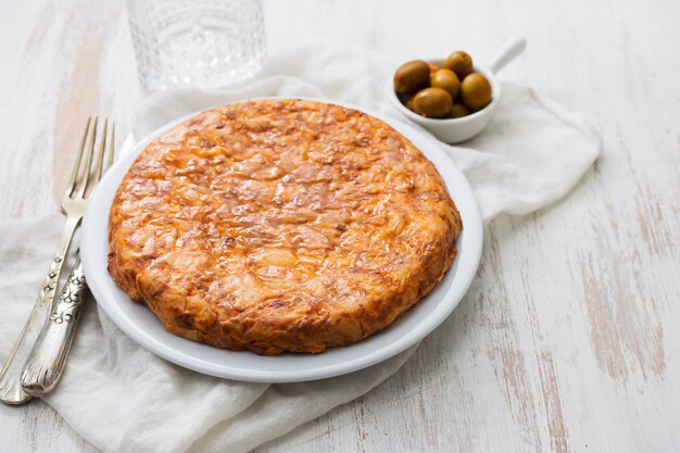 Comida típica espanhola Tortilla em prato branco sobre fundo branco de madeira