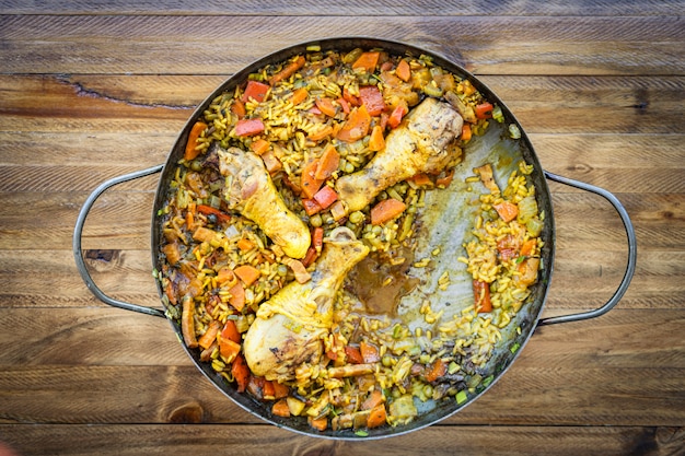 Comida típica española de Arroz con pollo o paella de pollo en una paellera a la que le falta una porción. Concepto de comida étnica o regional.