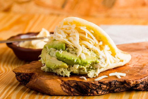 Comida típica latinoamericana, arepa para desayunar con queso, aguacate y pollo