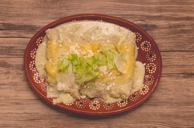 Comida típica mexicana enchiladas verdes sobre mesa de madera