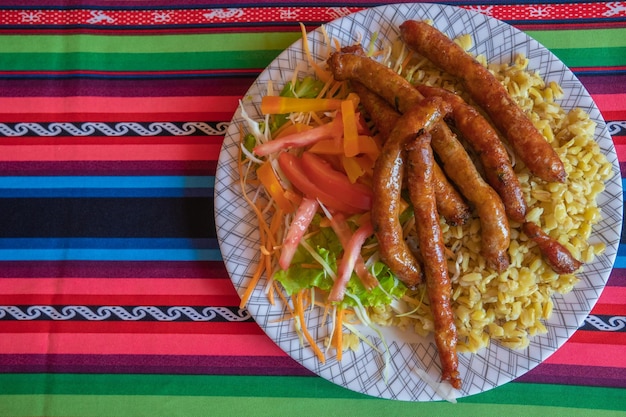 comida tradicional boliviana chorizos de Tarata plato con ensalada de trigo y verduras en un aguayo