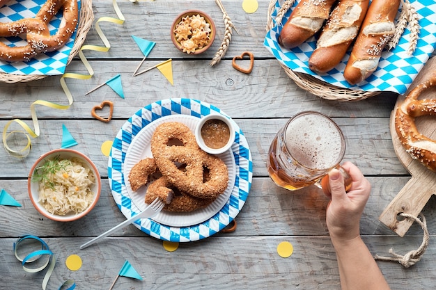 Comida tradicional da Oktoberfest, plana deitada na mesa de madeira com decorações bávaras azuis e brancas.