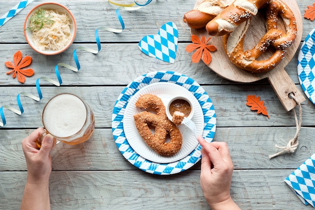 Comida tradicional da oktoberfest, plana deitada na mesa de madeira com enfeites de papel azul e branco.