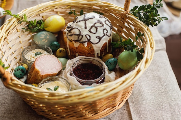 Comida tradicional de Páscoa na cesta Pão de Páscoa caseiro ovos de páscoa tingidos naturais presunto beterraba manteiga queijo na mesa rústica com flores de primavera Vista superior